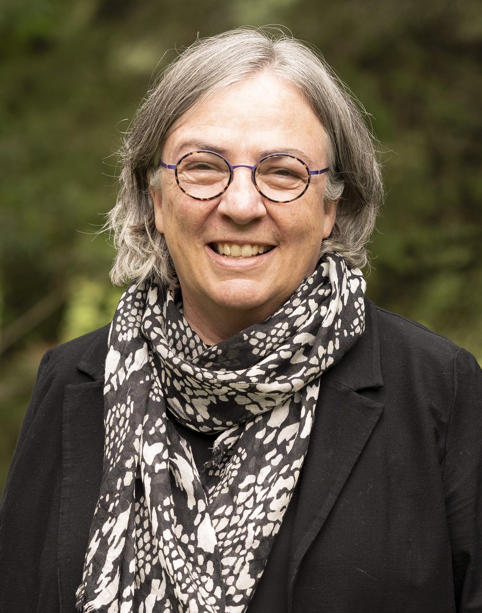 Head and shoulders view of Dr. Gillian Siddall outside wearing a black blazer and a white and black patterned scarf