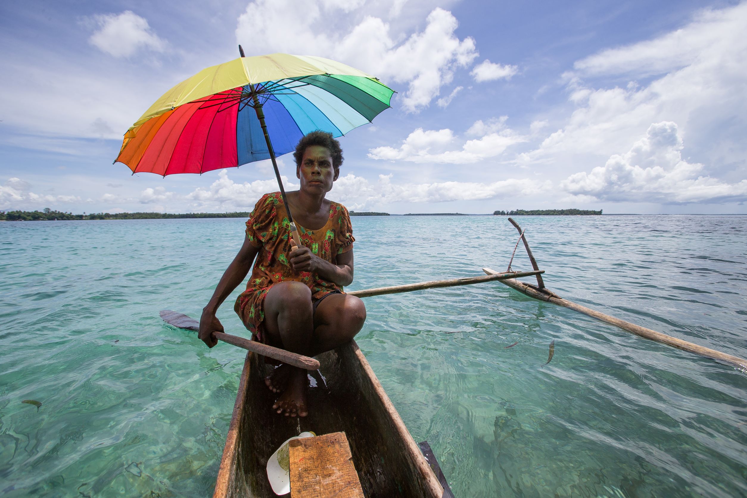 A woman off the northeastern islands of Papua New Guinea paddling a dugout canoe