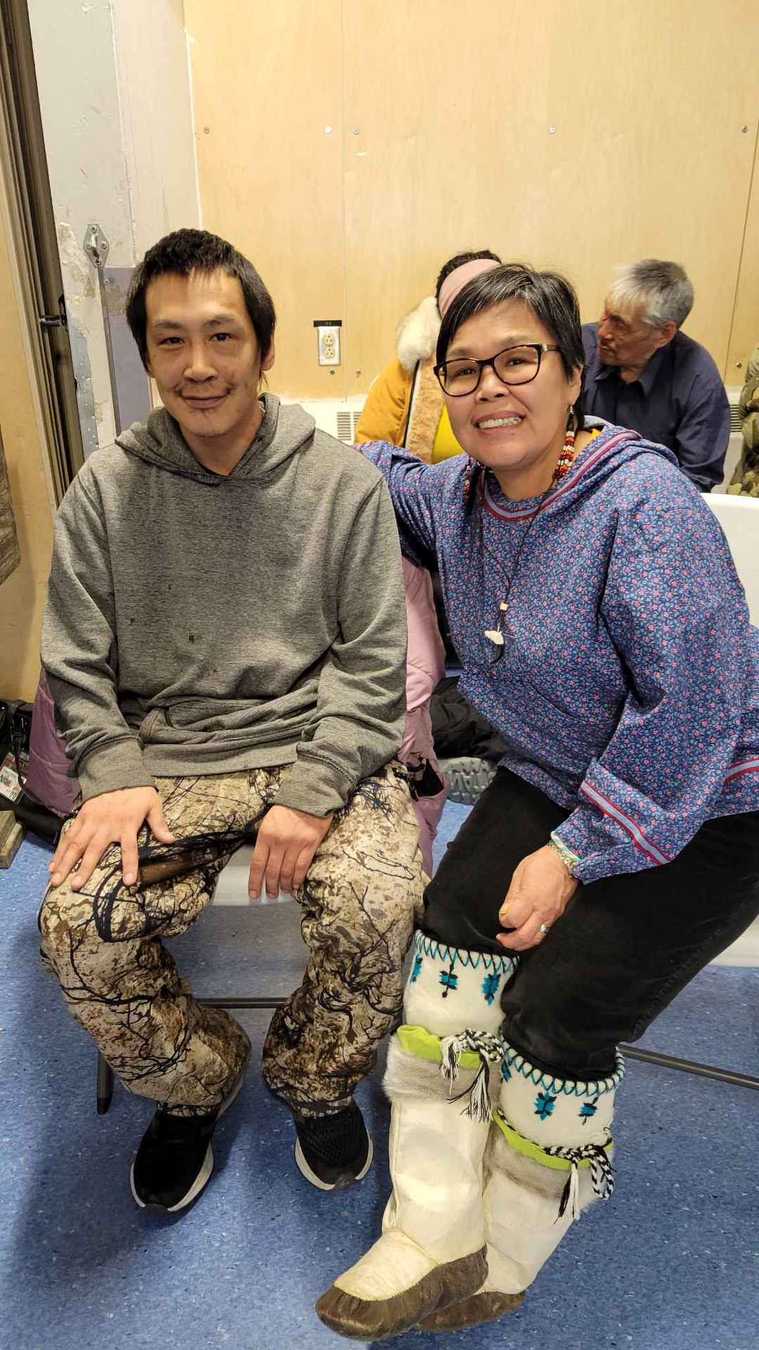 Lori Idlout sitting beside a constitutent with her arm around his shoulders