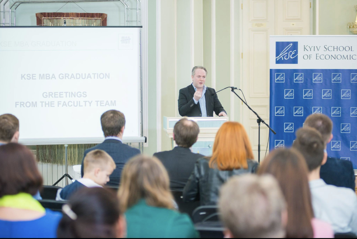 Mark Sawchuk giving a presentation at a podium for the Kyiv School of Economics