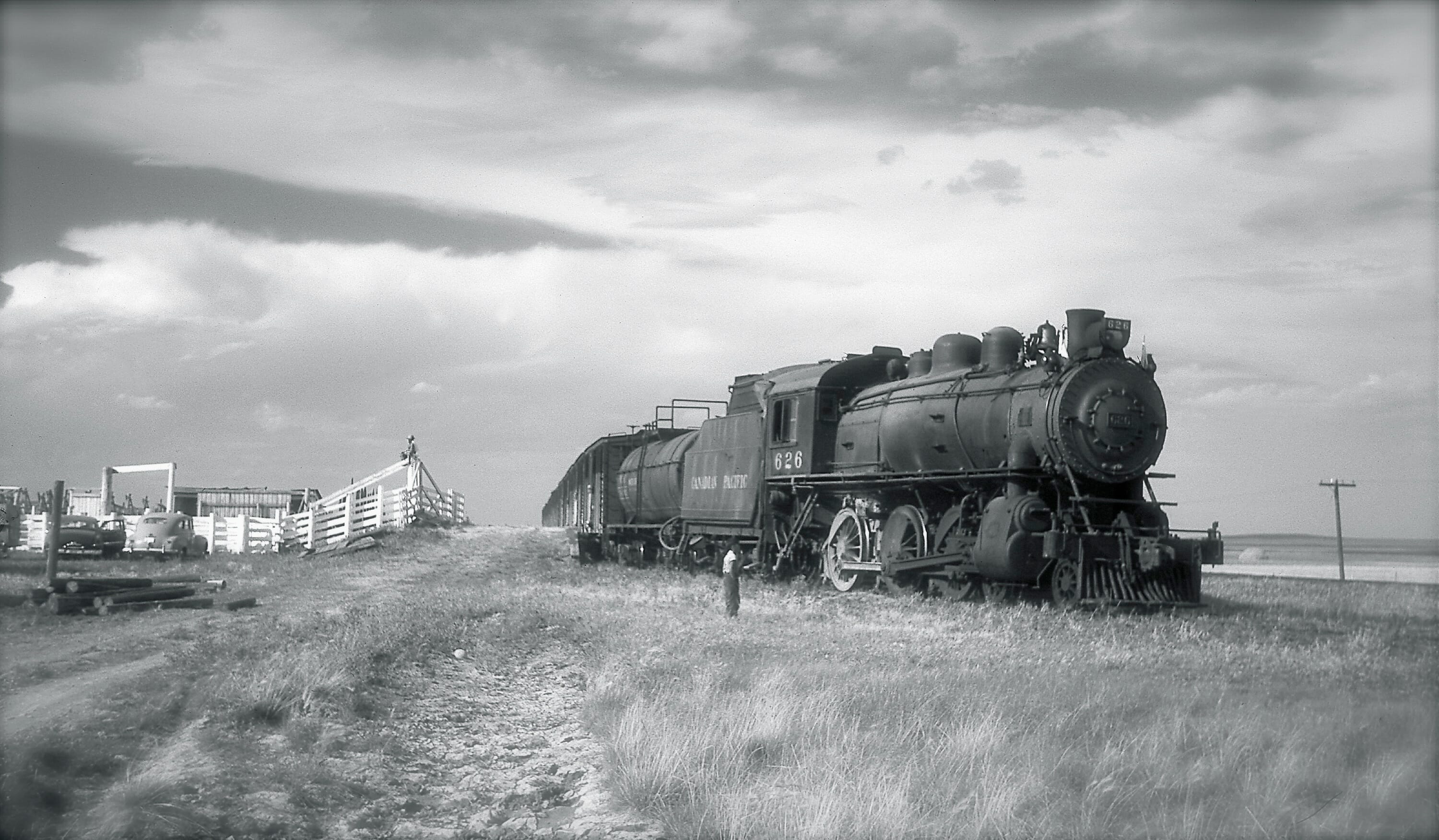 A black-and-white photo of Stephen Low as a child examing a locomotive in southern Alberta c. 1958