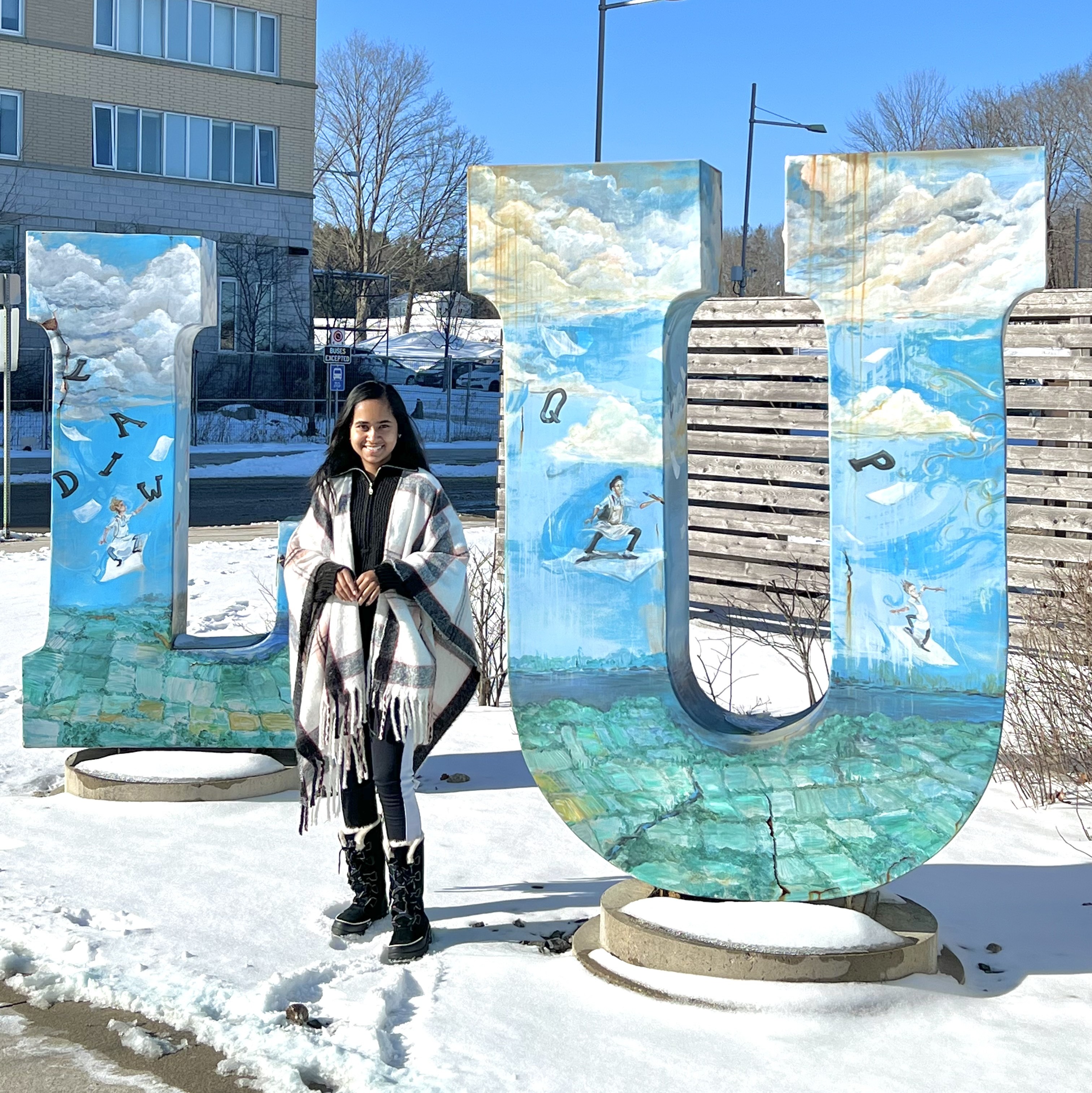Rechal Parmar by LU Sculpture Rechal Parmar, wearing a shawl, winter boots, and black clothing, stands outside by the "LU" Sculpture on snow-covered ground
