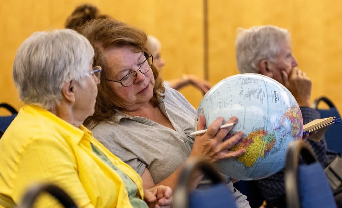 2026 TALL Geographic Literacy Event A seated older woman holds a globe while another seated older woman looks on