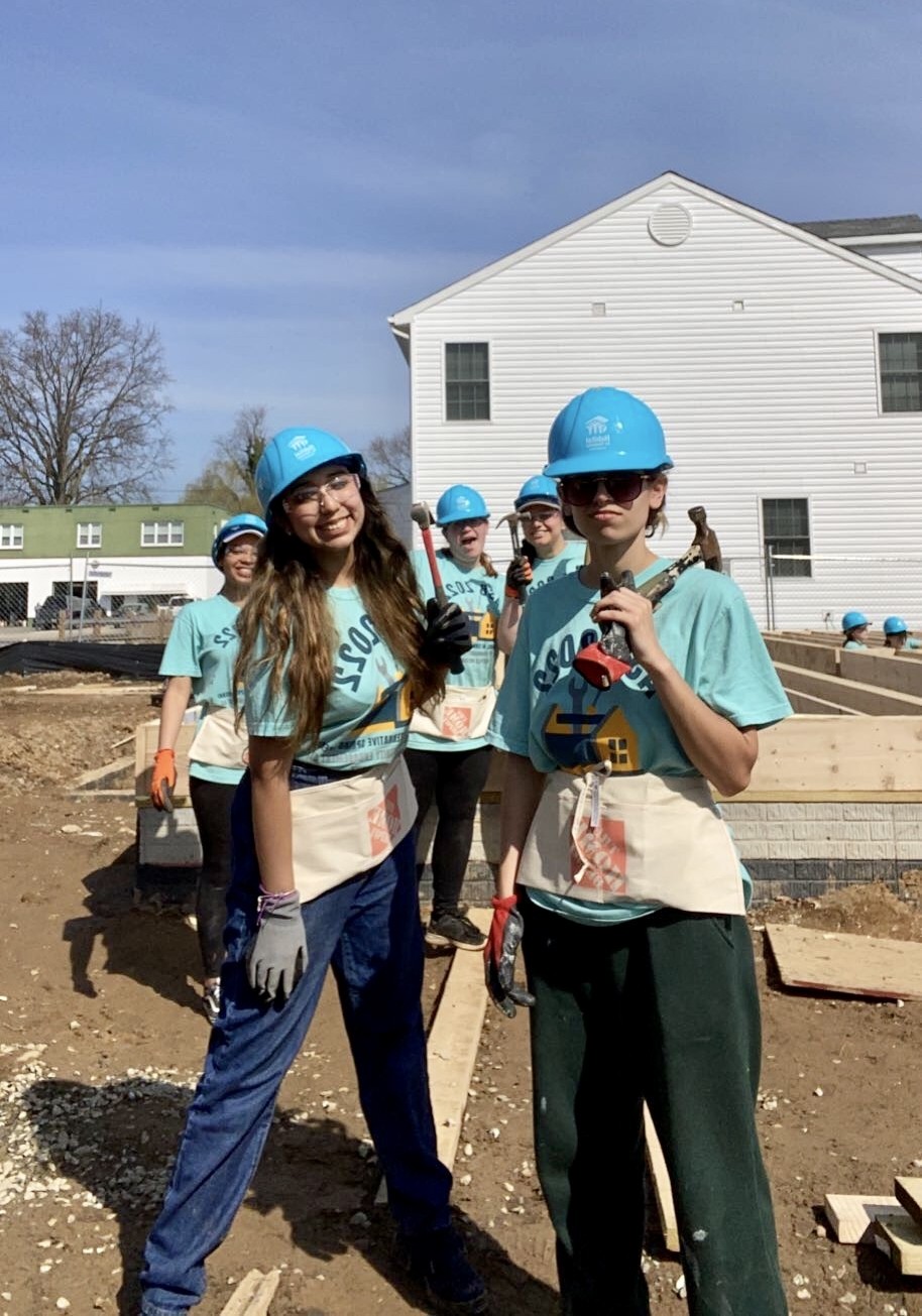 Aliss Chavarri Builds a Home Aliss Chavarri and four other women wearing blue hardhats and holding hammers stand on the grounds of a construction site