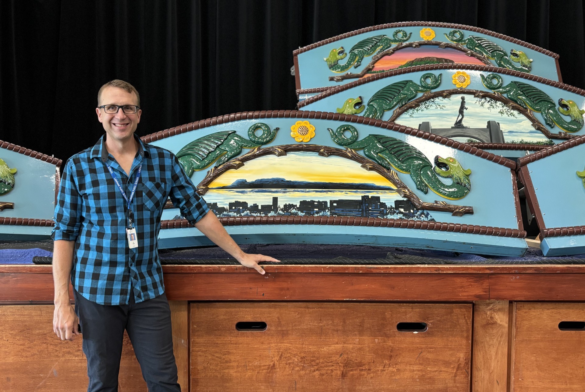 Keith Ailey with Chippewa Park Carousel Panels Keith Ailey stands in front of painted carousel panels propped up on a stage