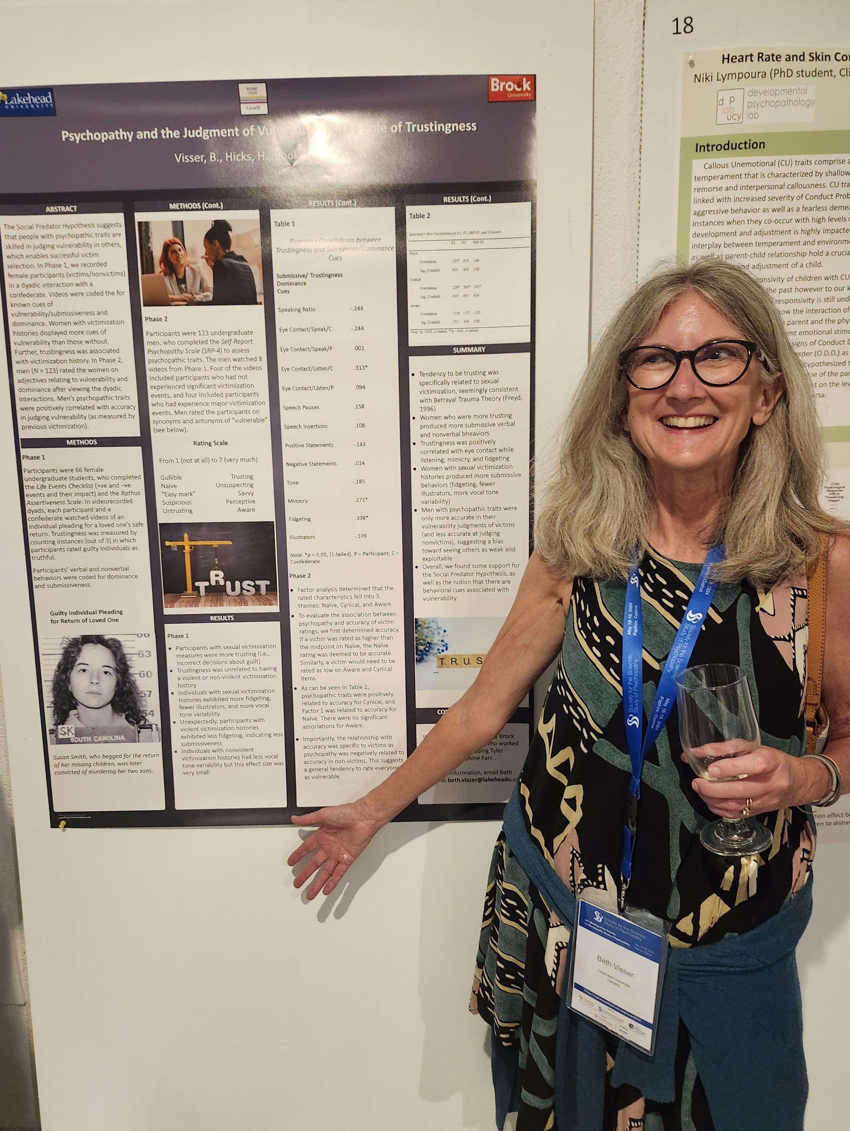 Dr. Beth Visser stands in front of a research poster about the social predator hypothesis 