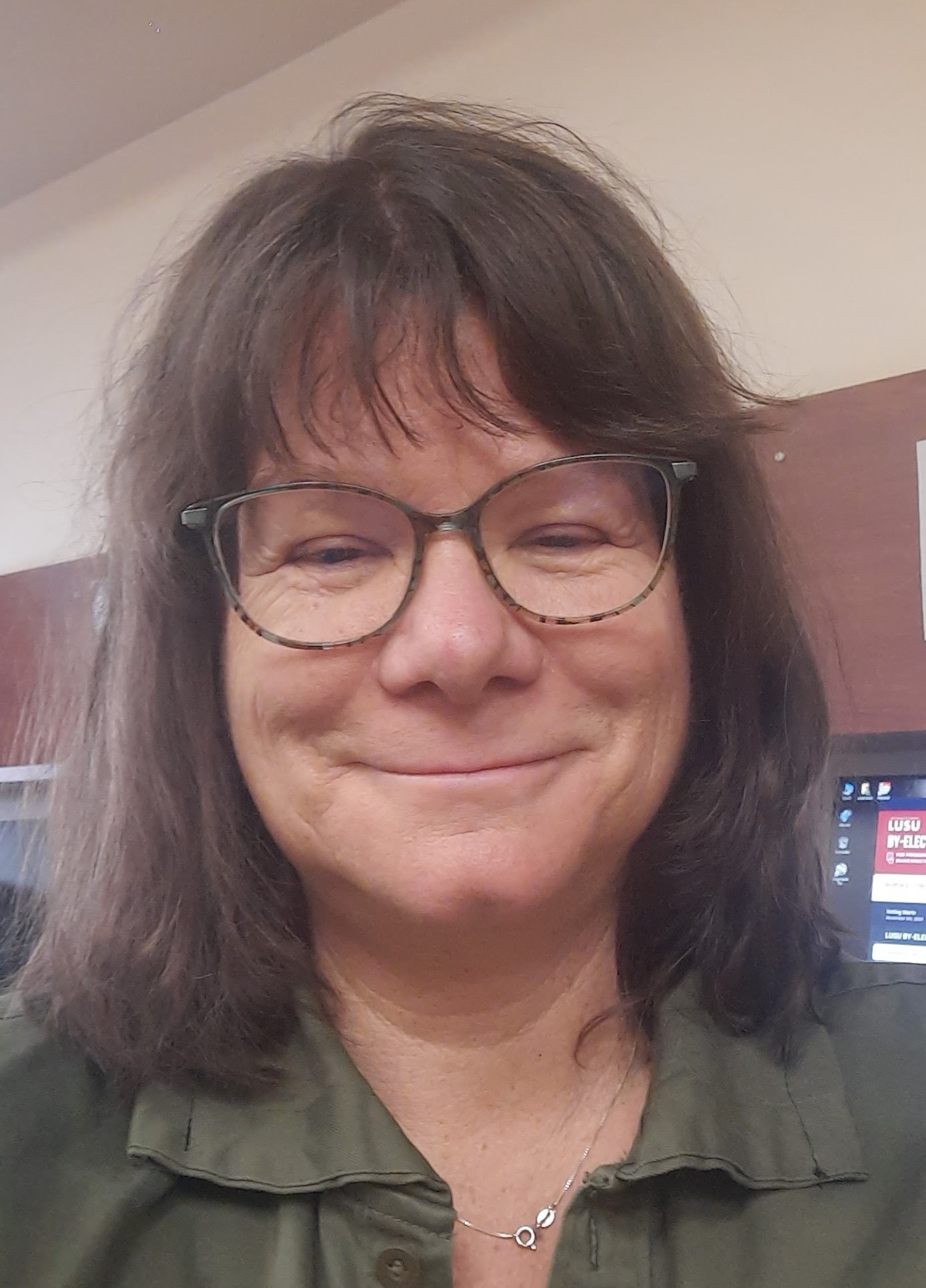 A head-and-shoulders photo of Linda Grant wearing a green blouse, silver chain, and glasses