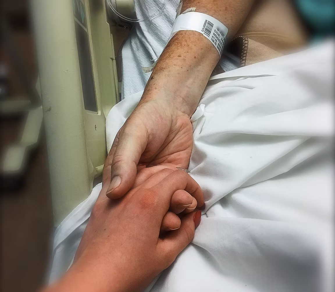 Holding Hands in Hospital A close-up image of someone in a hospital bed holding the hand of someone else