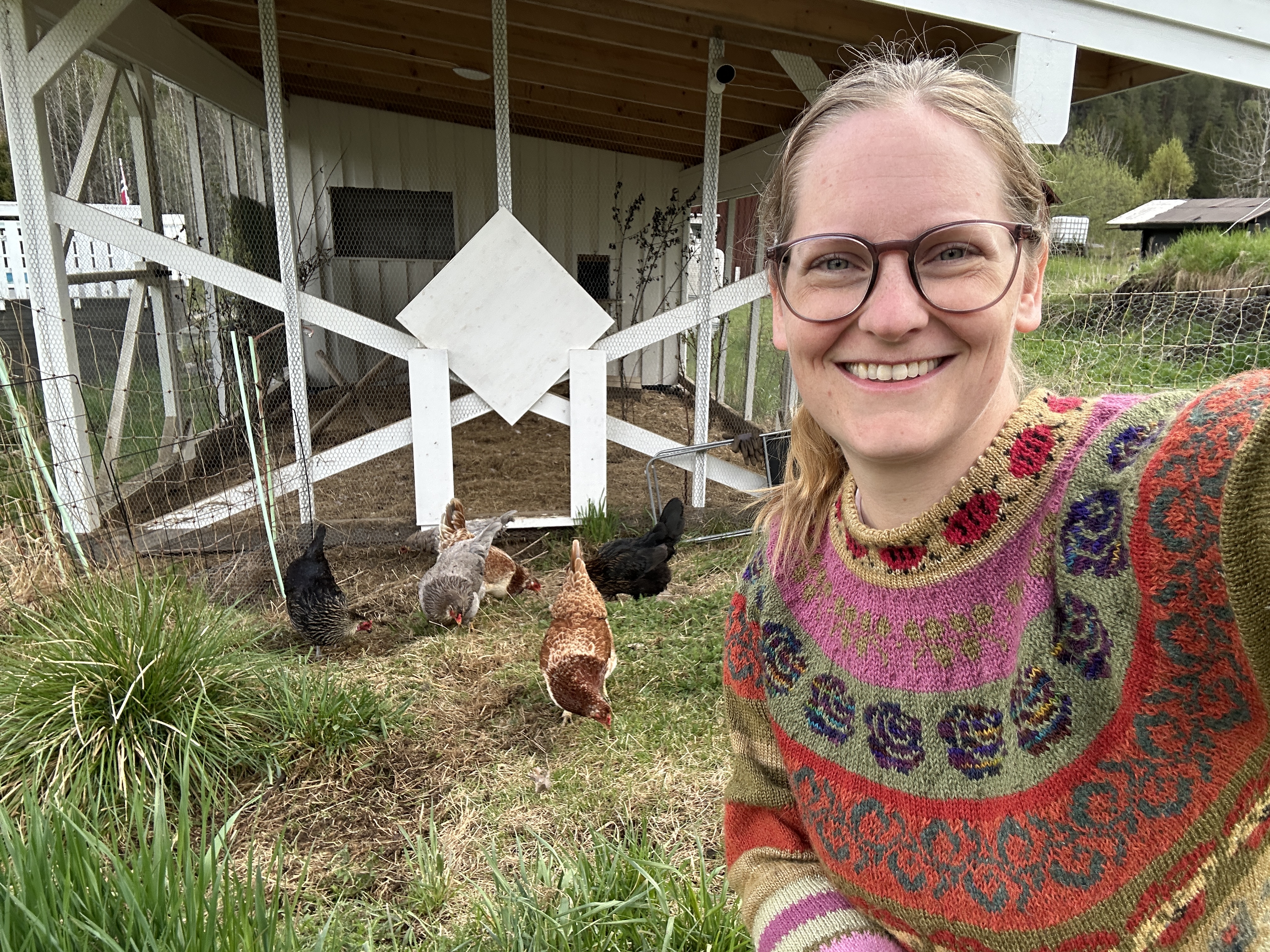 Kate Solbakk with Chickens Kate Solbakk, wearing a colourful patterned sweater, takes a selfie of herself by chickens and a chicken coop