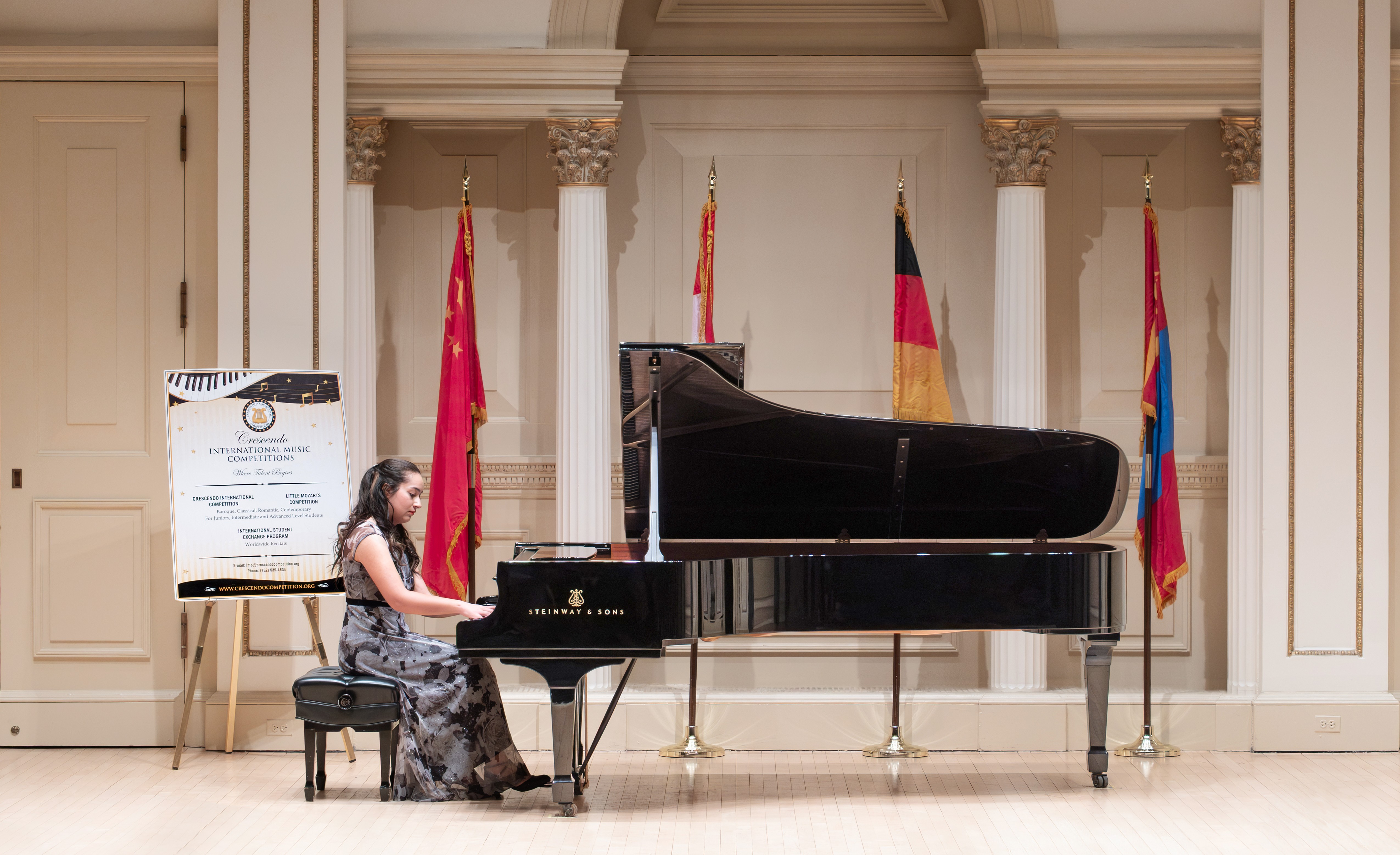 Mary Clark plays a Steinway & Sons piano in Carnegie Hall with flags and ornate stone columns in the background