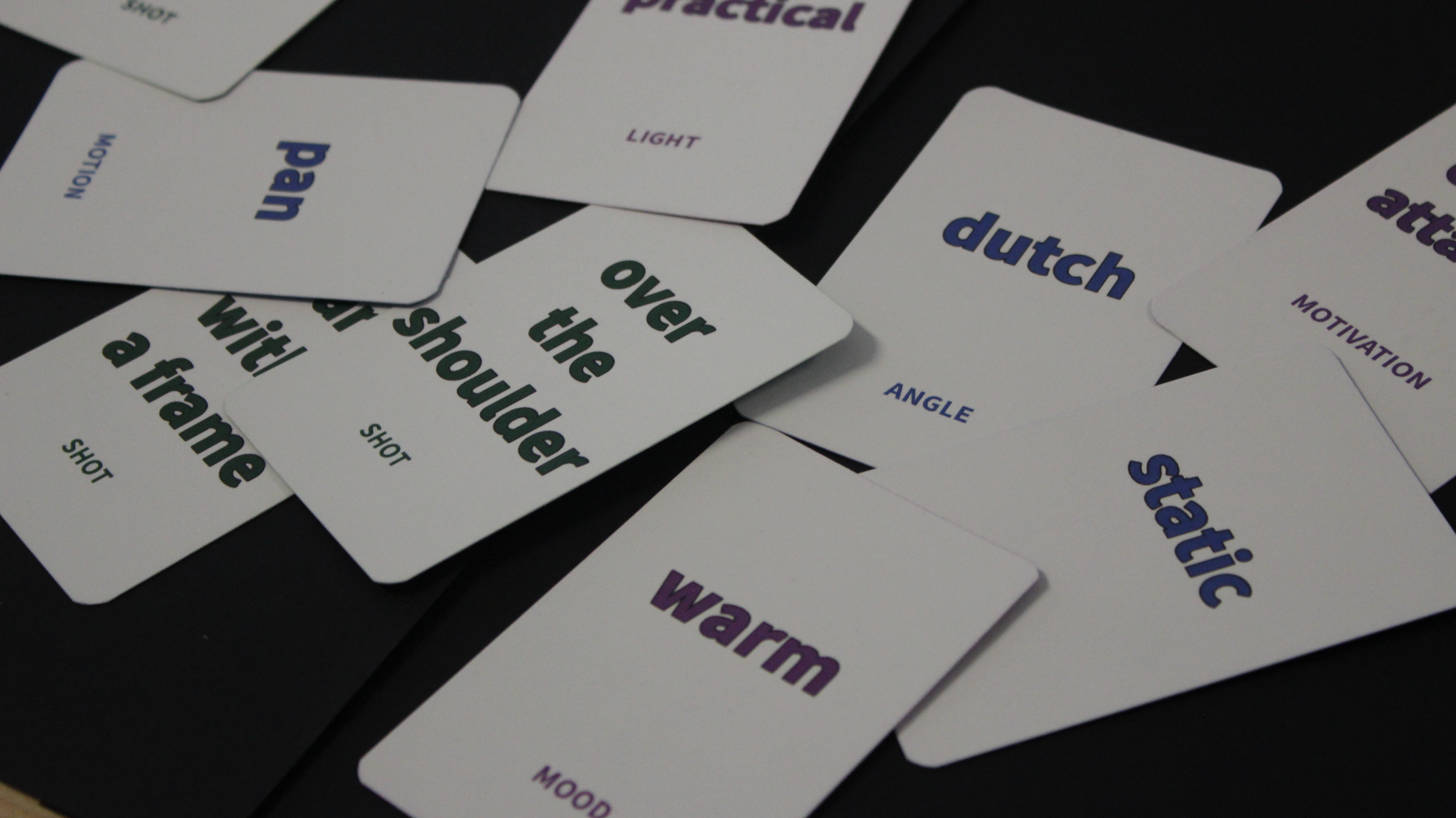 Scattered white cards with words printed on them sit on a black surface