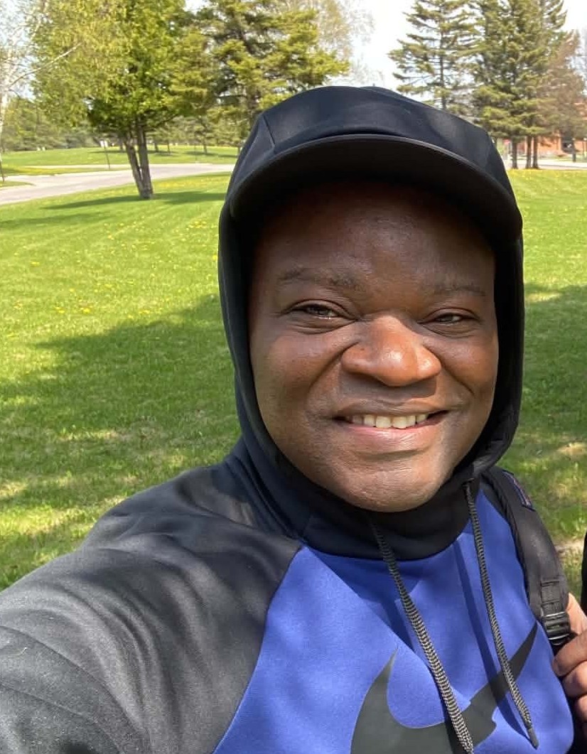 Omotunde Adeniran Omotunde Adeniran stands on a lawn in summertime wearing blue-and-black Nike hoodie