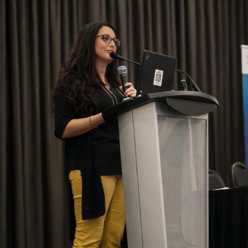 Tamara Bernard stands at a podium holding a microphone