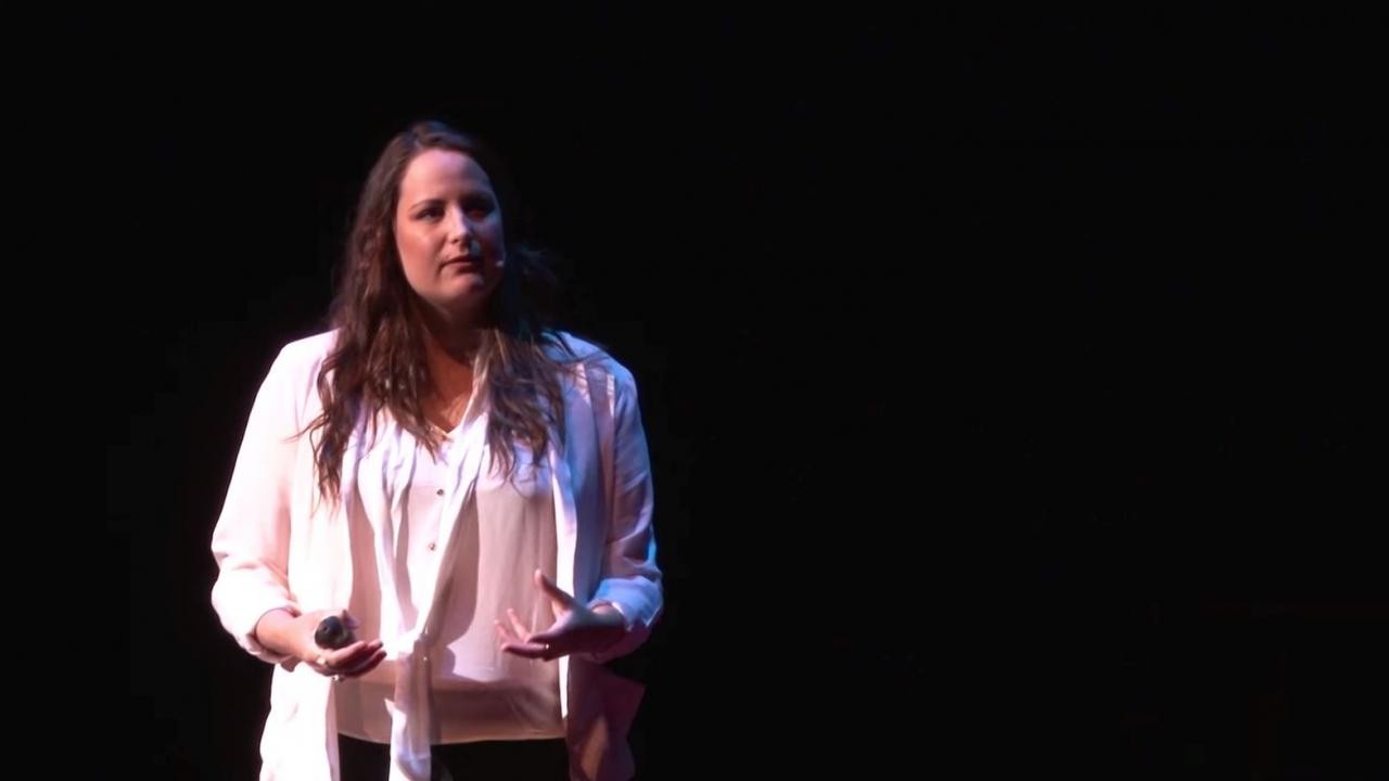 Tamara Bernard holds a microphone in one hand and gestures with her other hand