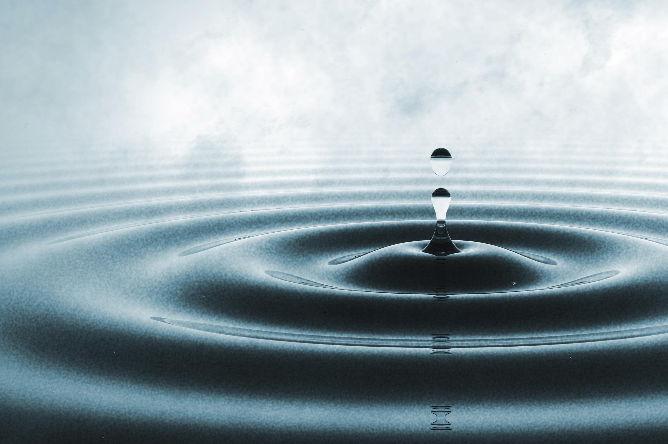 This is an image of a drop of water falling into water making ripples
