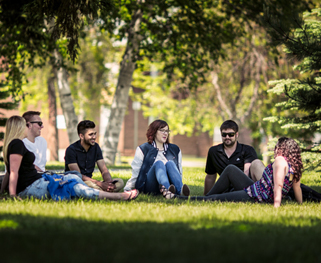 Six students hanging out in the shade on Lakehead campus
