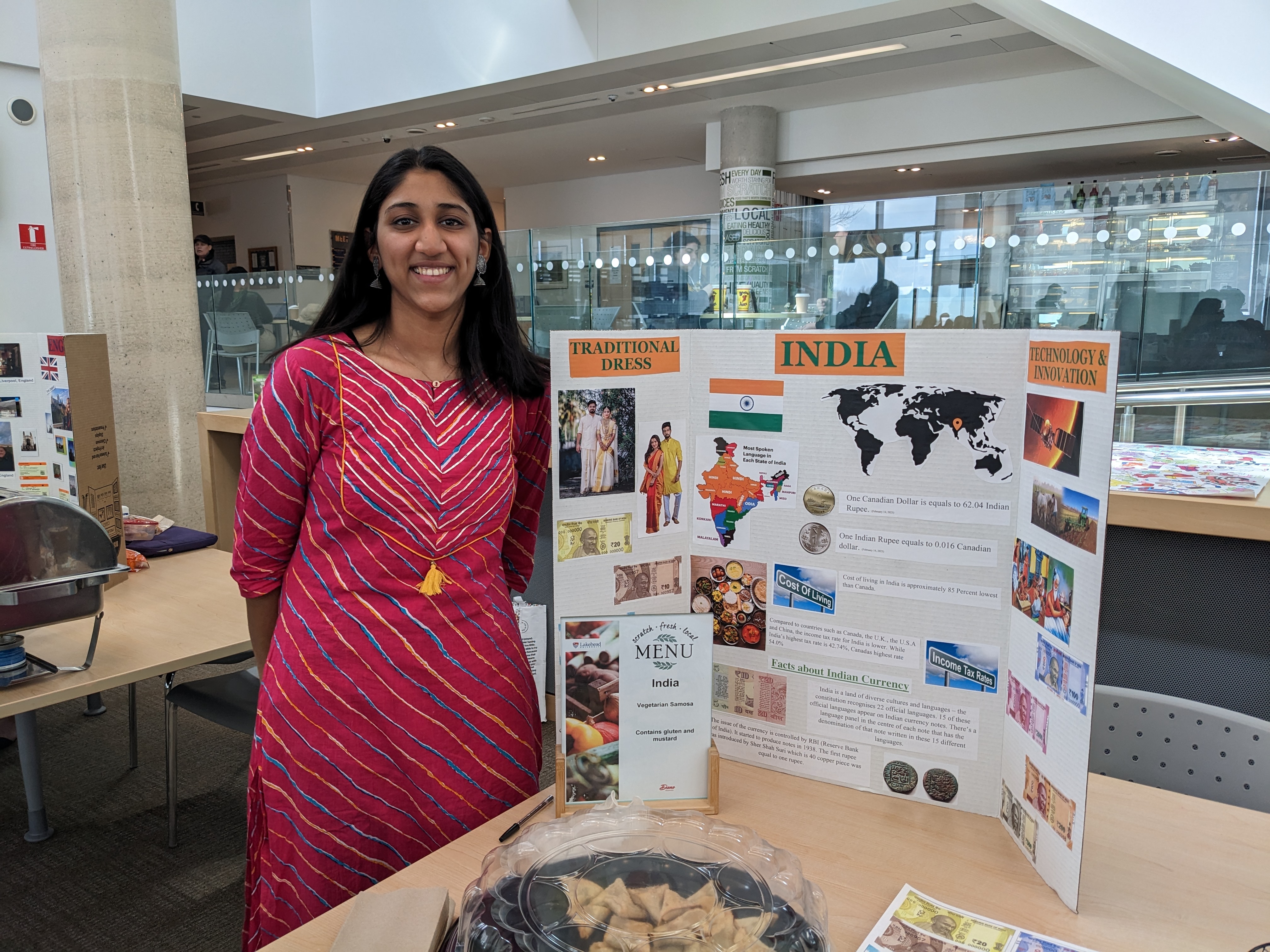 Welcome the World 2023 - India A student dressed in traditional Indian clothes stands beside their table display representing the country of India.