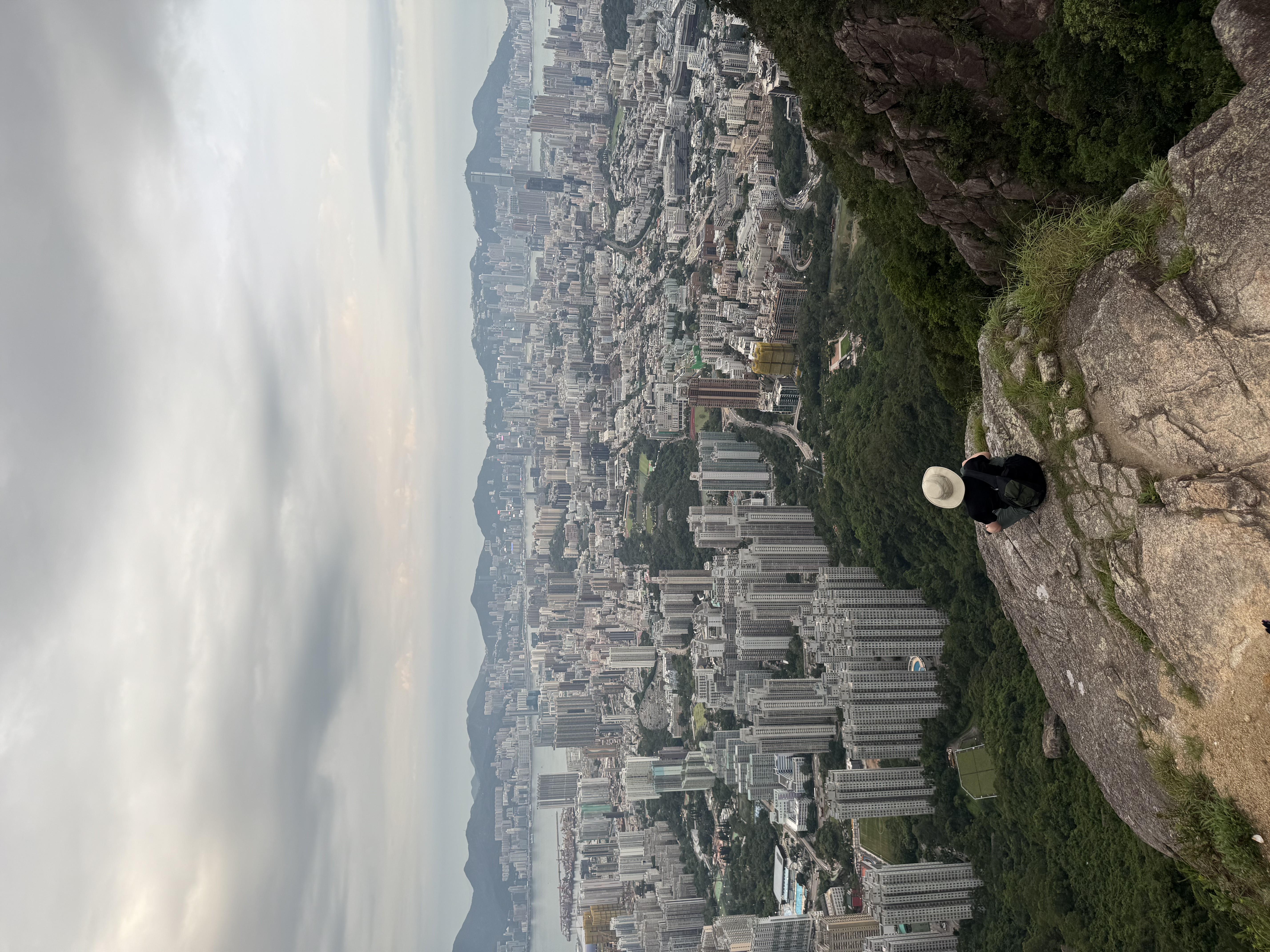 exchange student sitting on edge of rock above city view