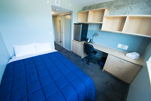 Inside one of our residence rooms in Orillia, displaying a desk area, bed and fridge
