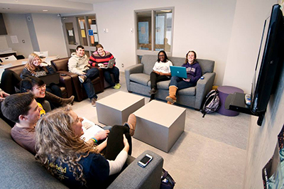 Students in a residence lounge watching tv and laughing