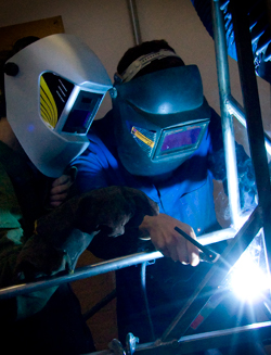 A teacher instructing a students welding
