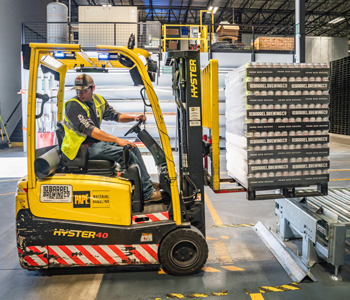 Photo of a forklift operator moving a skid of product